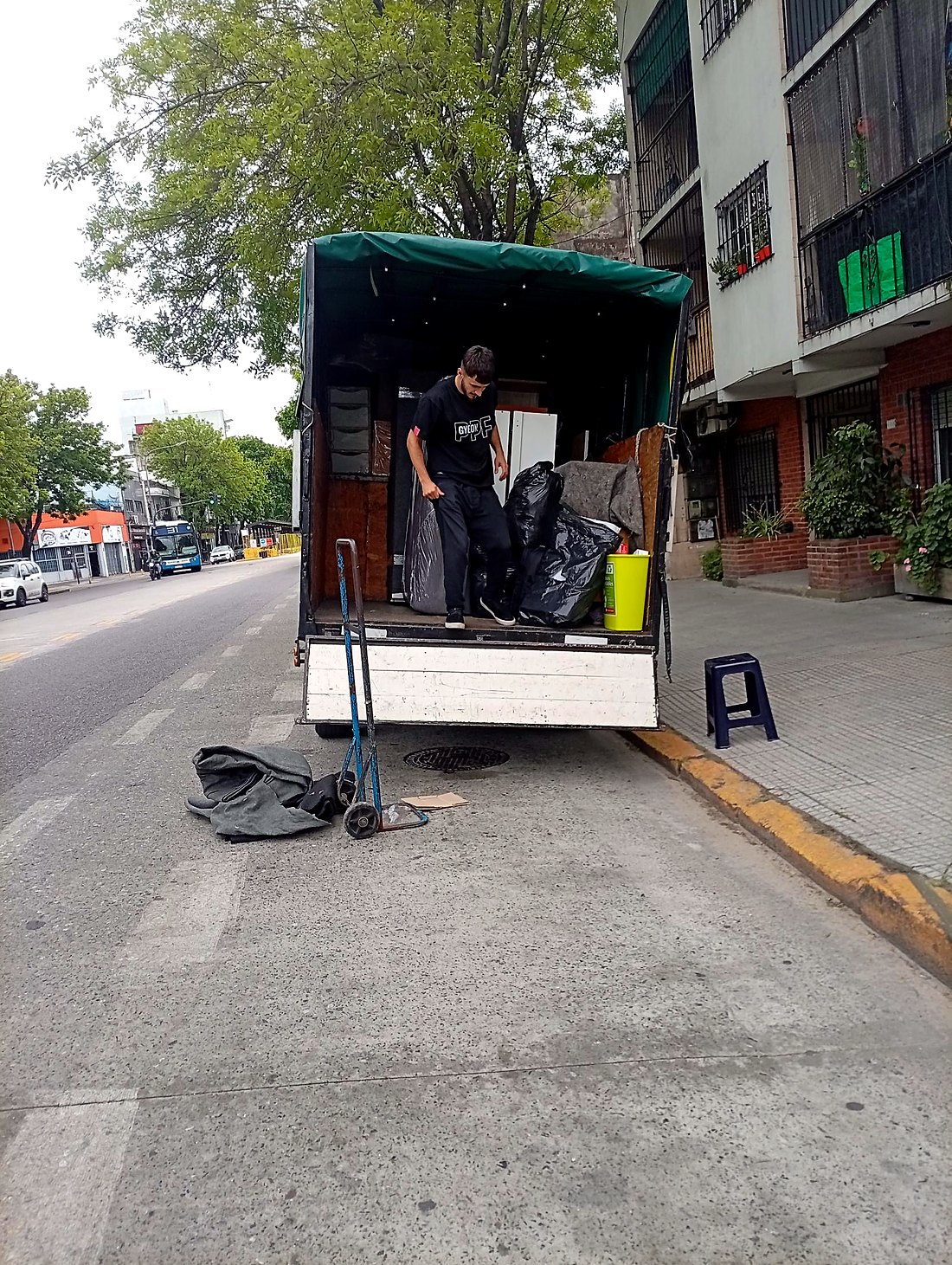 Integrante del equipo de Fletes More bajando del camión de lona verde con muebles cargados