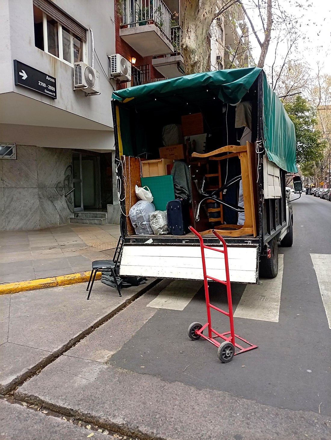 Camión de mudanza con muebles de madera, sillas y carro de carga rojo