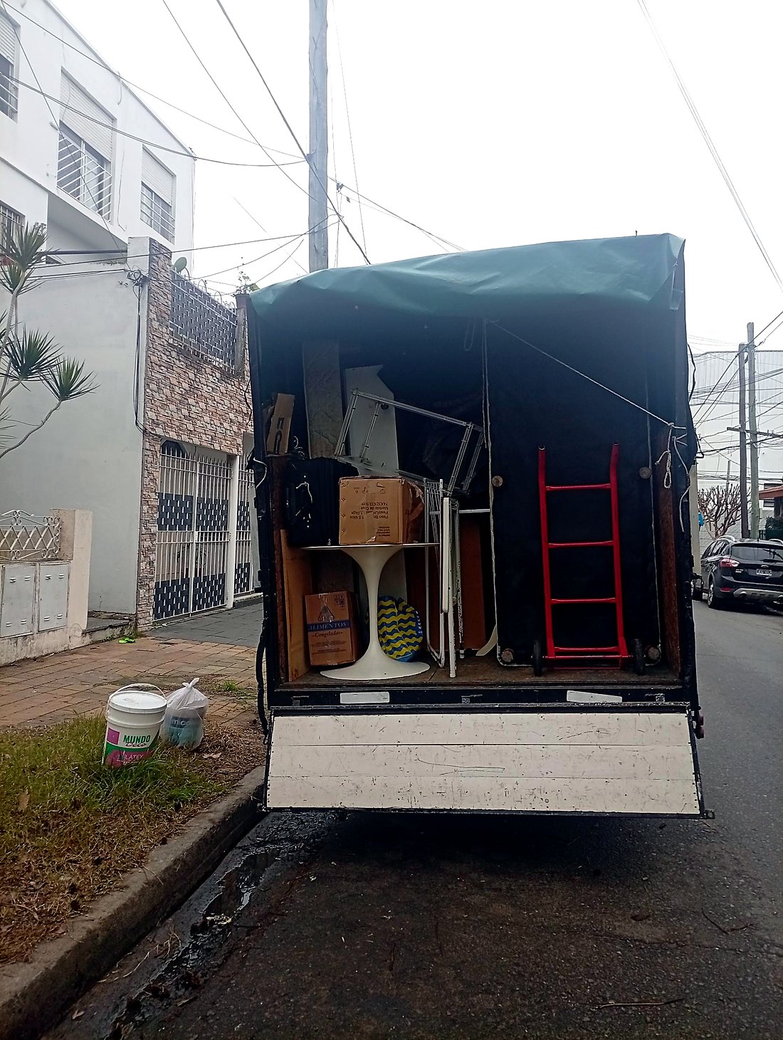 Camión con mesa tulipán blanca, cajas y bolsos cargados con cuidado